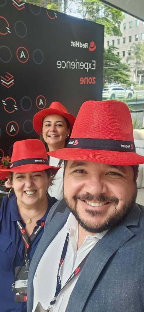 Equipe da Fast Lane presente no Red Hat Summit Connect São Paulo 2024, ao lado de banners de empresas parceiras como AWS, Microsoft e Google.